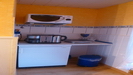 eine kleine Küche mit Kühlschrank, Mikrowelle, Kaffeemaschine und Induktionskochplatte ist ebenfalls vorhanden